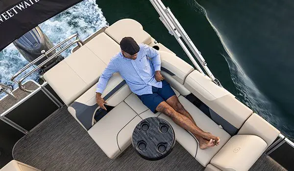 Aerial view of a man sitting on the stern seat on a Godfrey Sweetwater Cruise pontoon boat.