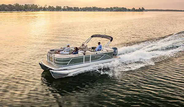Side profile of a Godfrey Sweetwater Cruise pontoon boat cruising across a lake.