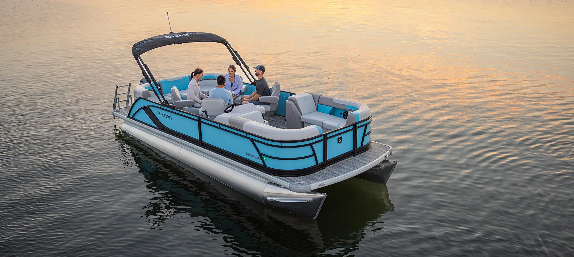 Aerial view of 4 people sitting at the stern table on a Godfrey Sweetwater Entertainment pontoon boat.