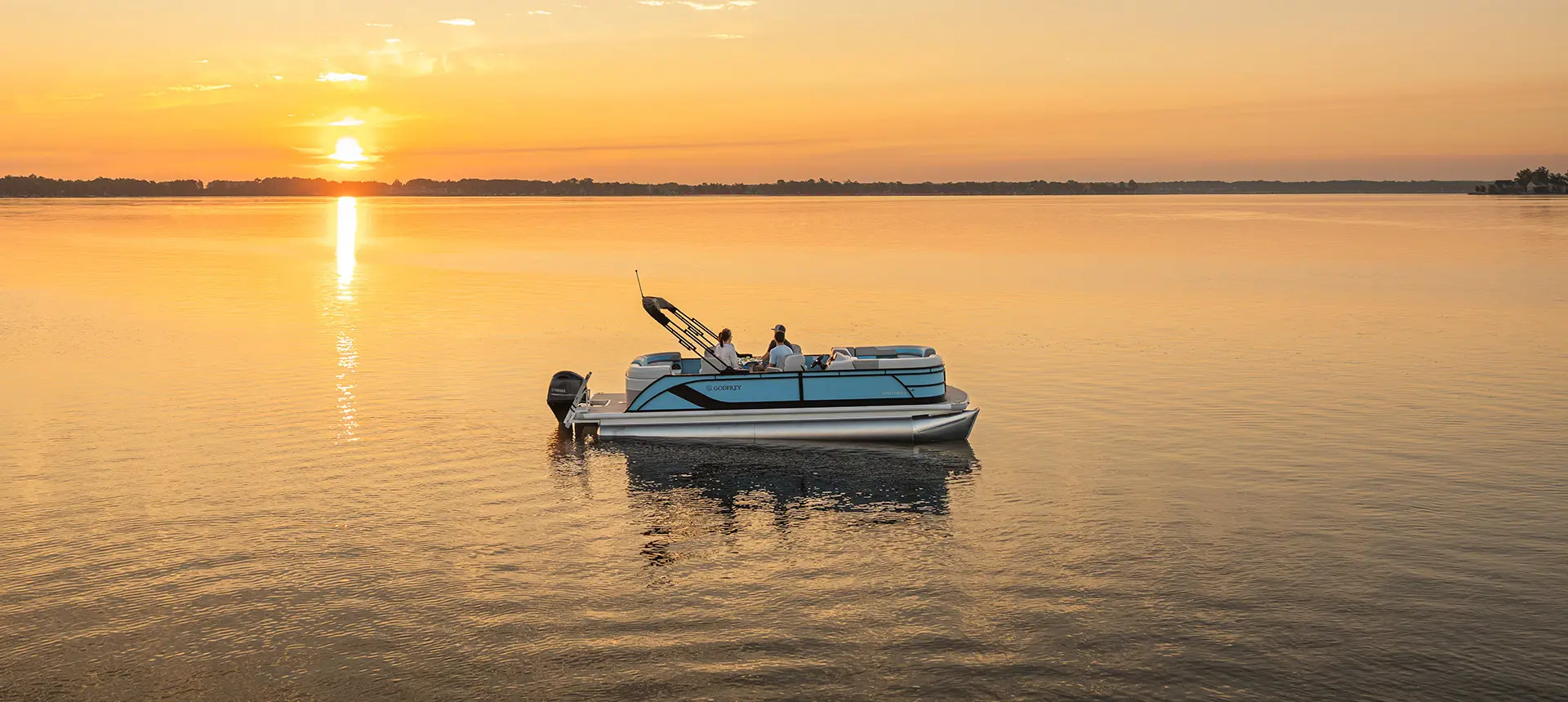 Aerial view of 4 people cruising the lake on a Godfrey Sweetwater Entertainment pontoon boat.