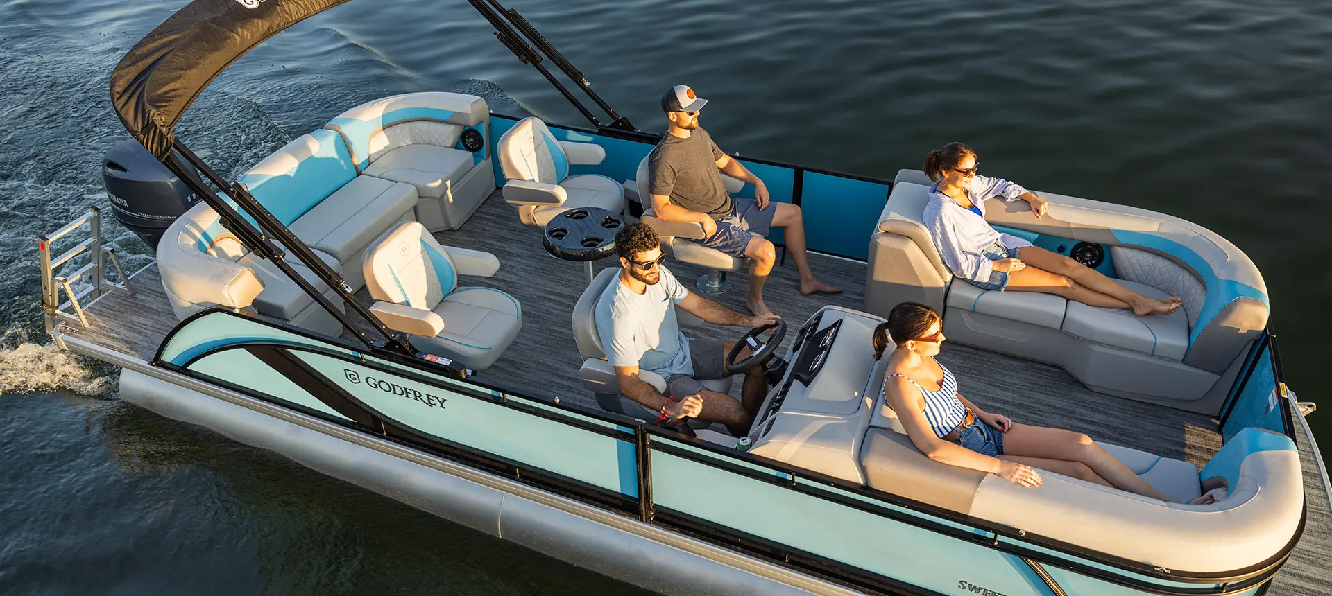 Side profile of a Godfrey Sweetwater Entertainment pontoon boat cruising on a lake.