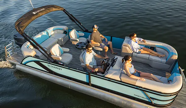 Side profile of a Godfrey Sweetwater Entertainment pontoon boat cruising on a lake.