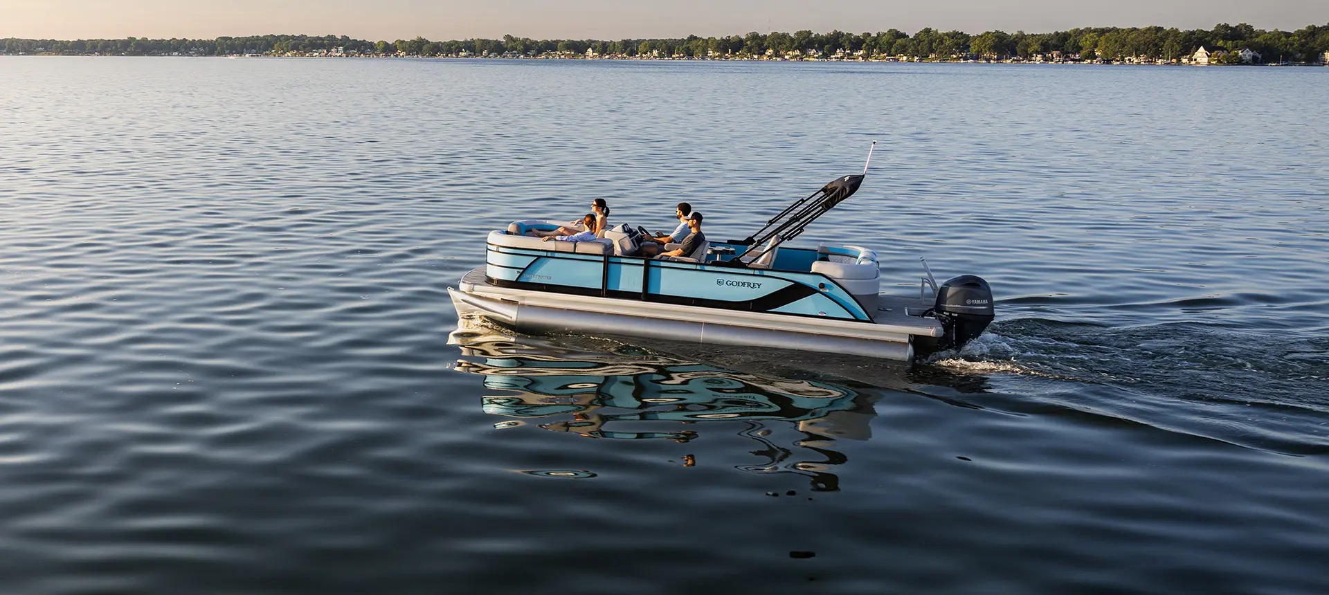Aerial view of a woman relaxing on the bow split bench seat on a Godfrey Sweetwater Entertainment pontoon boat.