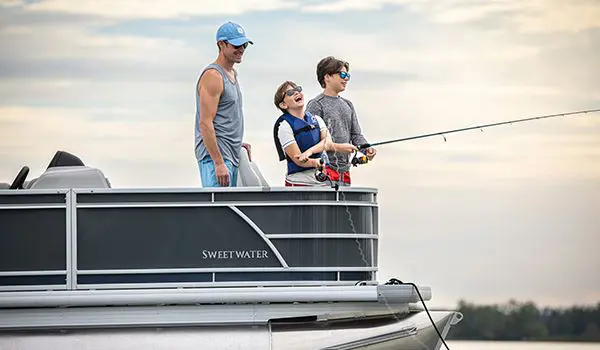 Two boys and their dad fishing off the bow of a Godfrey Sweetwater Fishing pontoon boat.