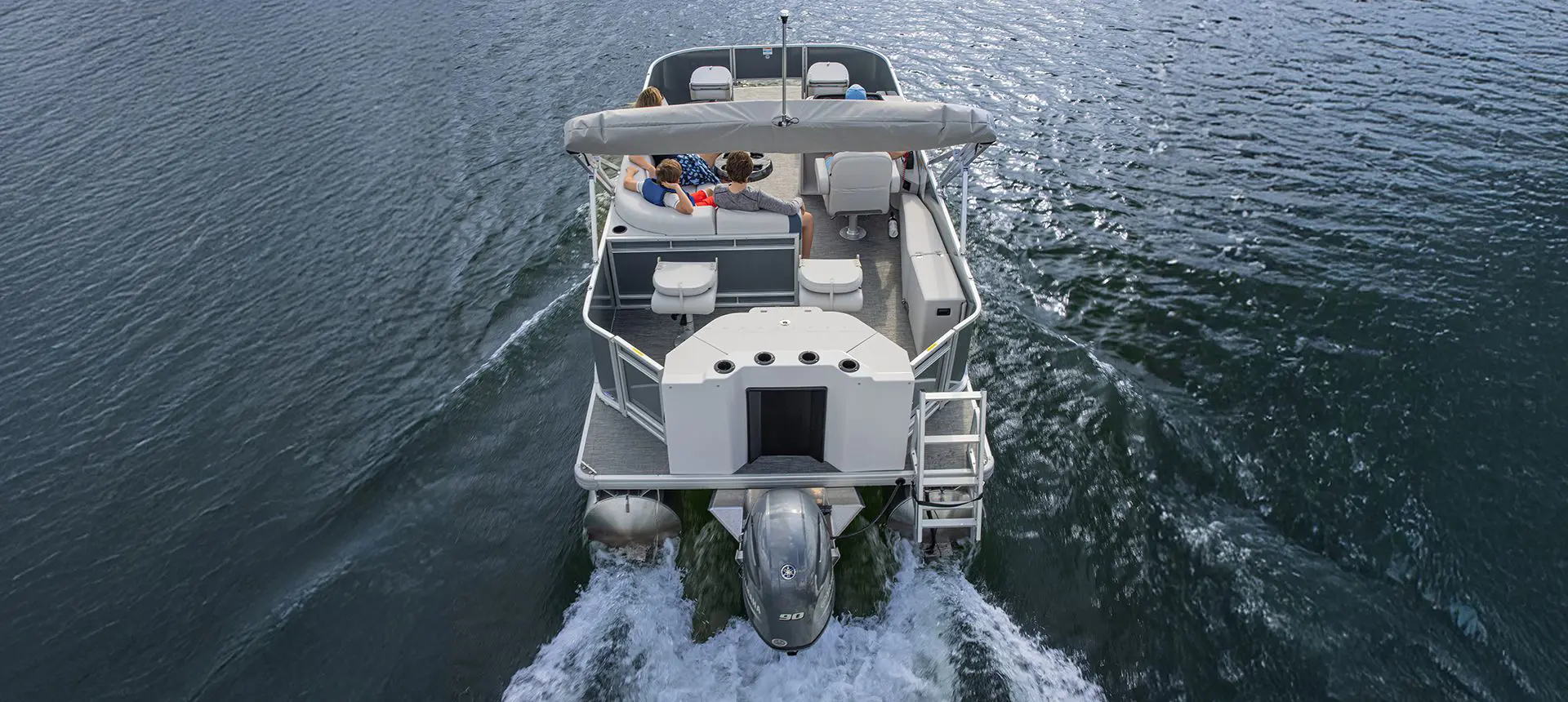 Stern focused view of a Godfrey Sweetwater Fishing pontoon boat cruising across a lake.