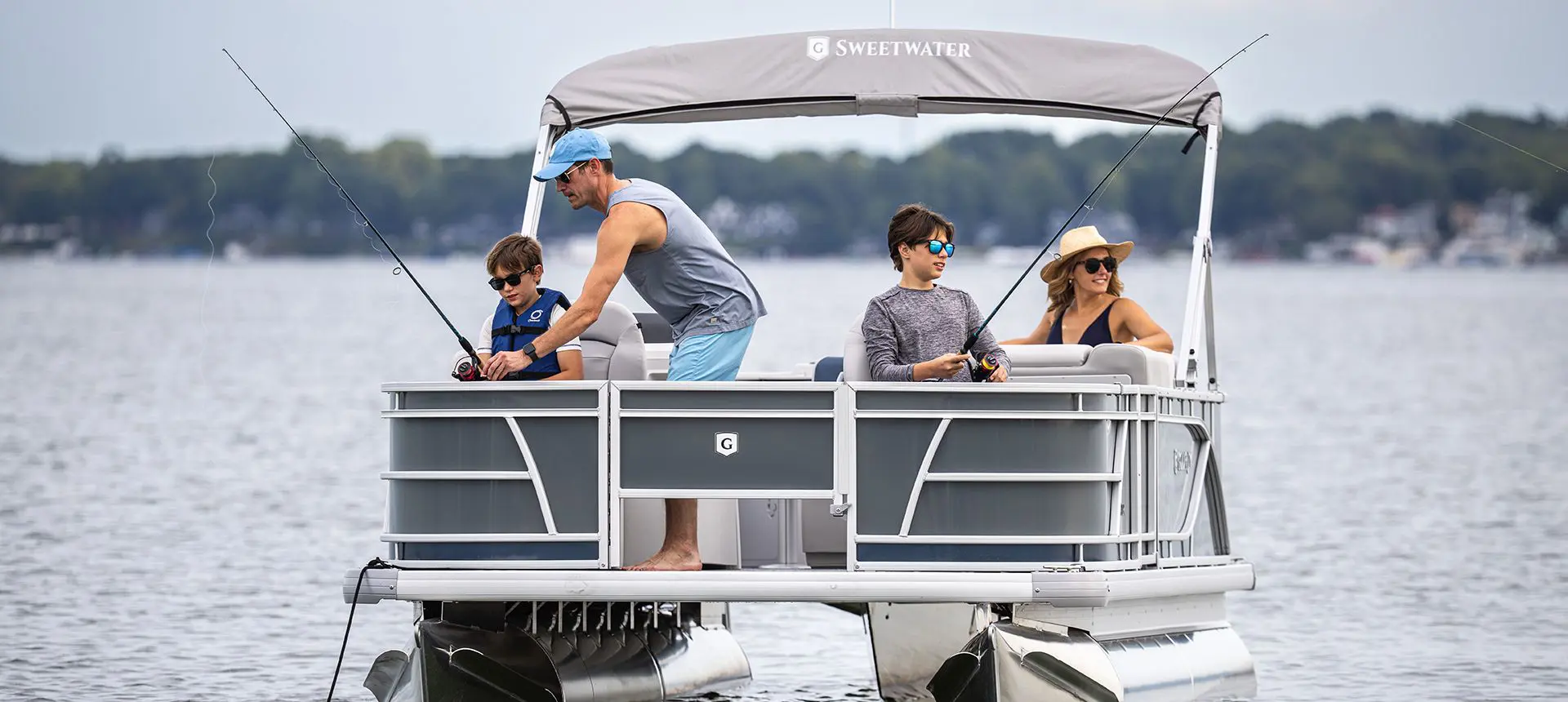 Dad helping his sons fish on a Godfrey Sweetwater Fishing pontoon boat.