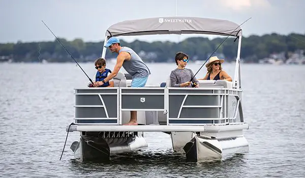 Dad helping his sons fish on a Godfrey Sweetwater Fishing pontoon boat.