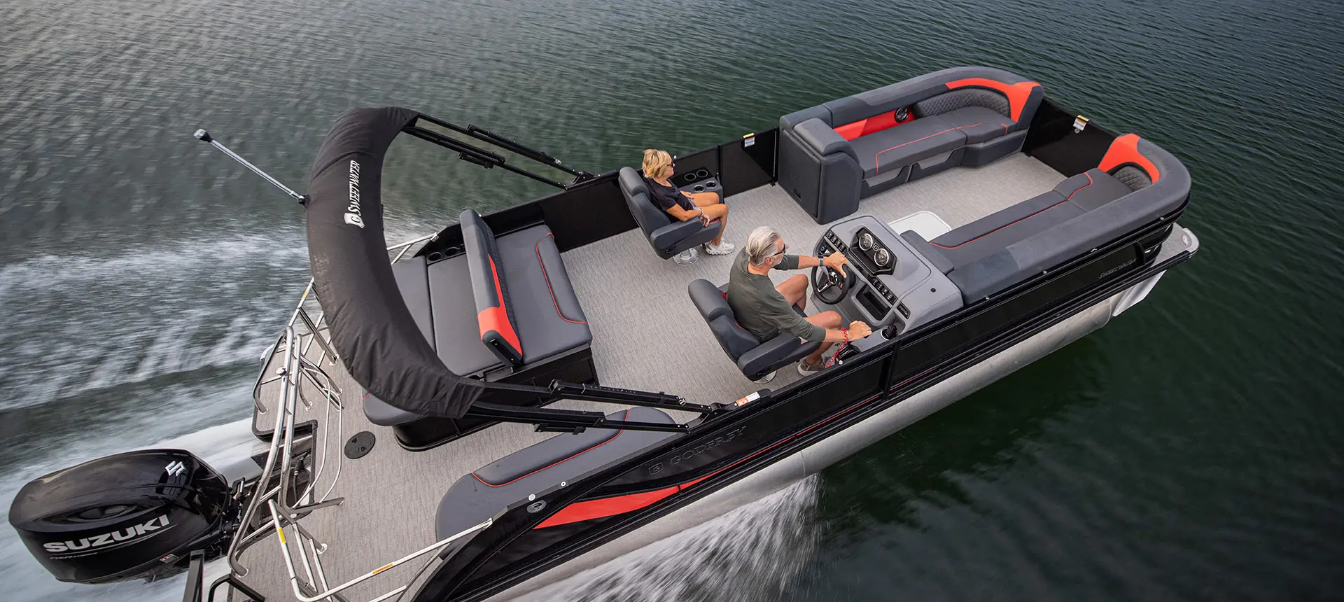 Aerial view of a couple cruising the lake on their Godfrey Sweetwater Lounge pontoon boat.