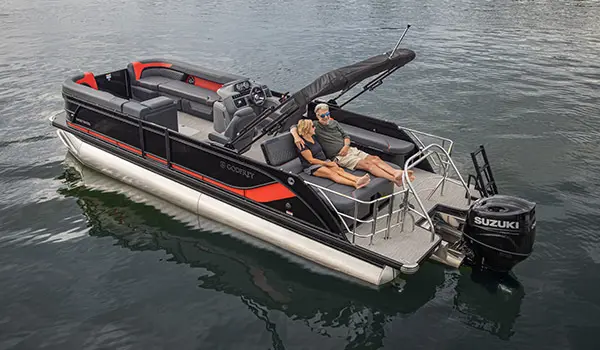 A couple relaxing on the stern lounge seating on a Godfrey Sweetwater Lounge pontoon boat.