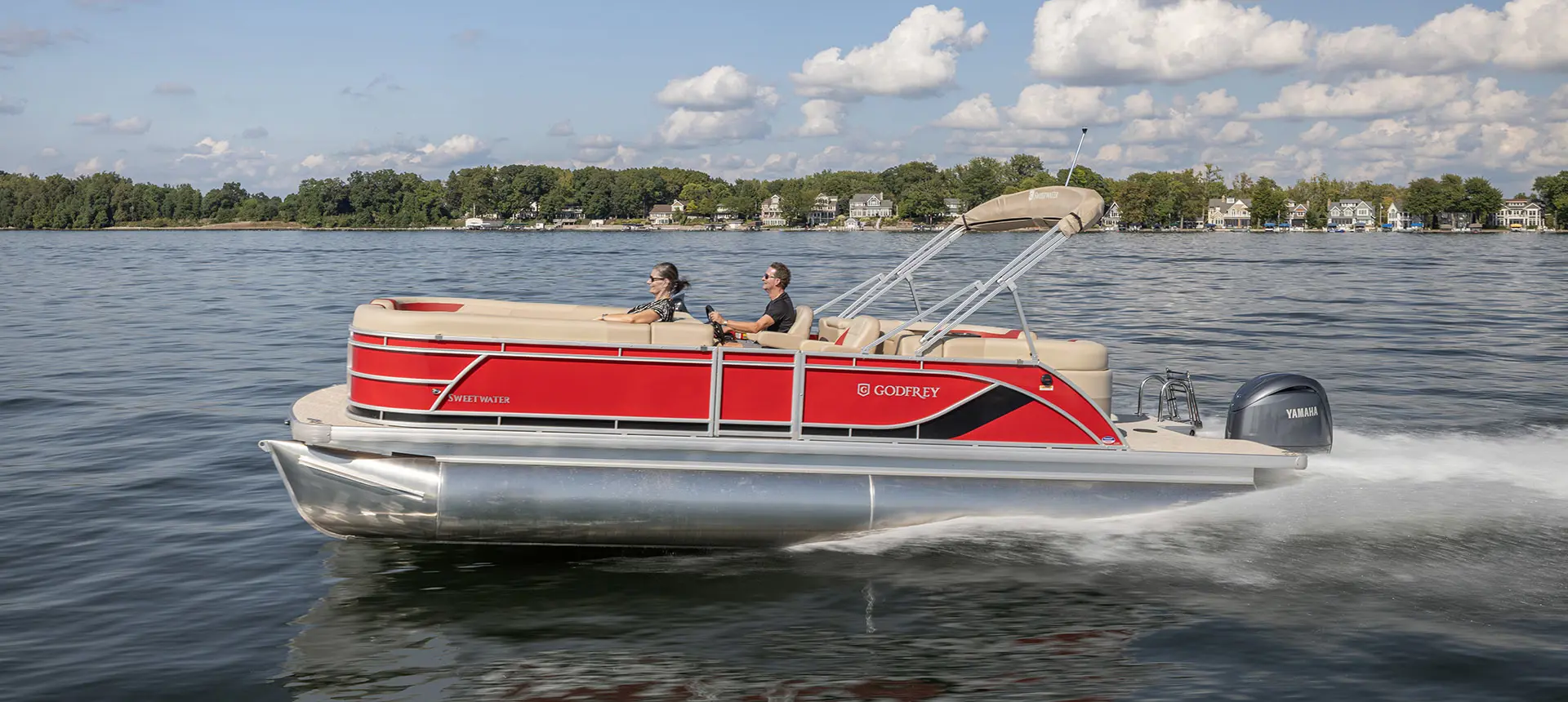 Side profile of a couple relaxing on a Godfrey Sweetwater Split Bench pontoon boat.