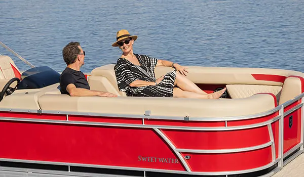 A couple relaxing on the bow seating of a Godfrey Sweetwater Split Bench pontoon boat.