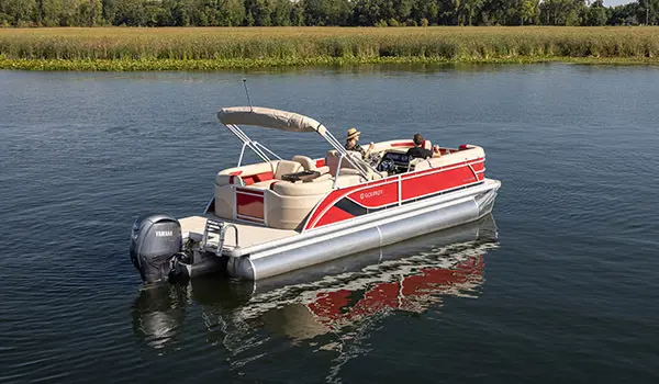 Side/stern focused view of a Godfrey Sweetwater Split Bench pontoon boat floating on a lake.
