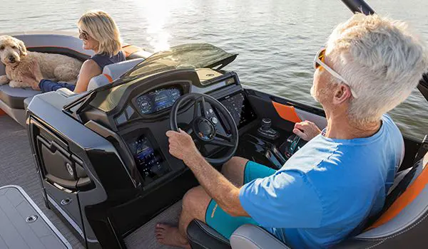 Man enjoying the comfort of the helm on a Godfrey XP Tritoon boat.