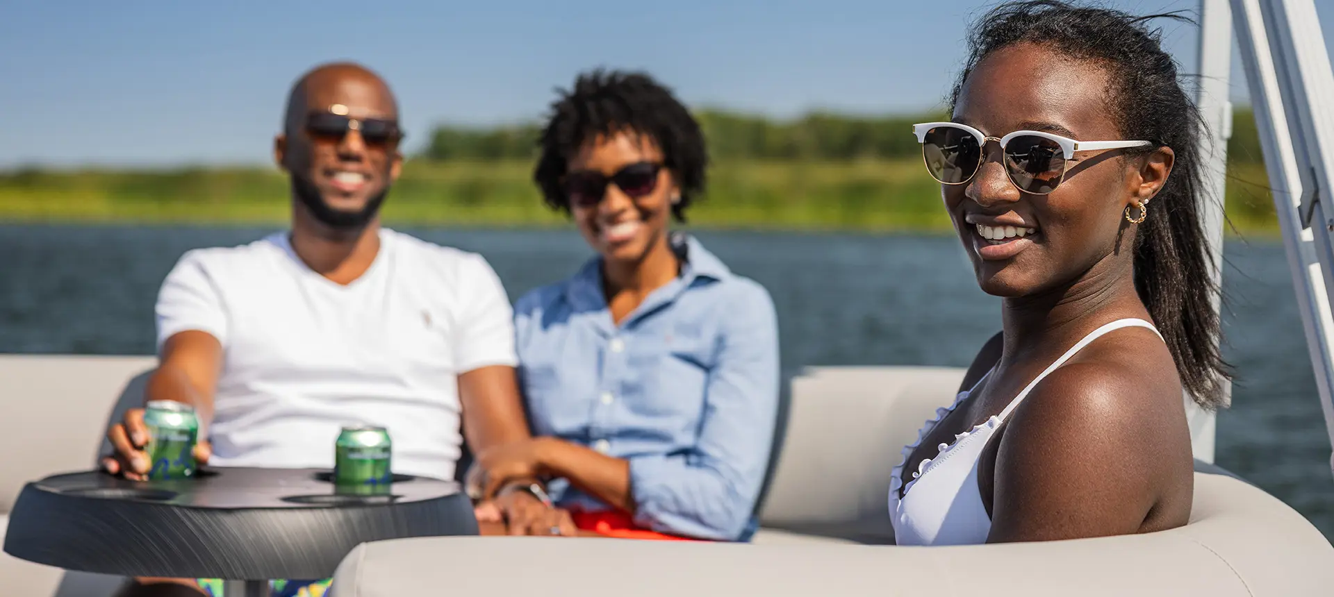 3 people sitting at the stern table on a Godfrey Xperience Cruise pontoon boat.