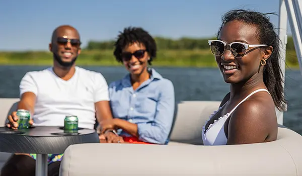 3 people sitting at the stern table on a Godfrey Xperience Cruise pontoon boat.