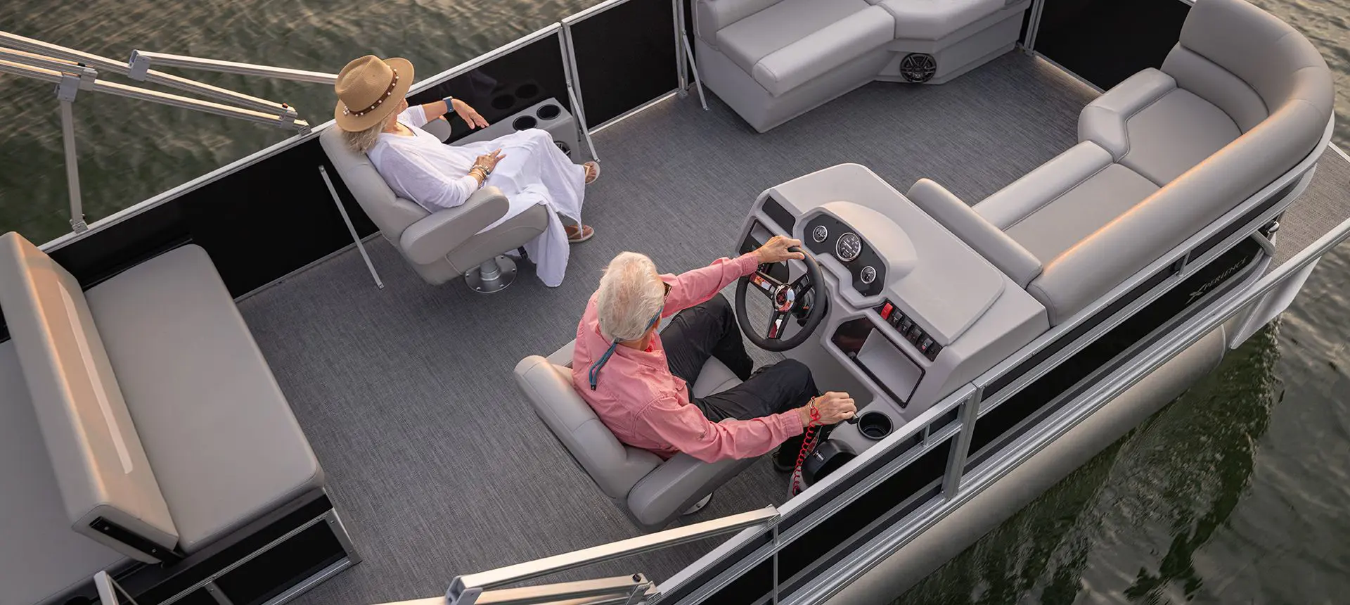 Aerial view of a couple sitting comfortably in the co-captain's chairs on a Godfrey Xperience Lounge pontoon boat.
