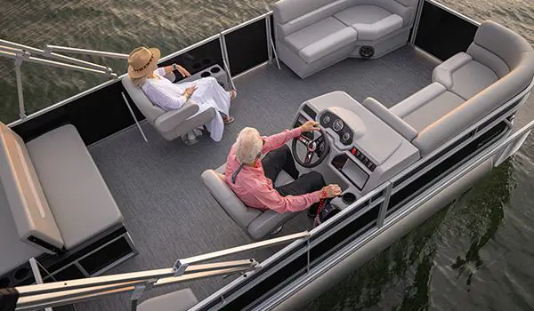 Aerial view of a couple sitting comfortably in the co-captain's chairs on a Godfrey Xperience Lounge pontoon boat.