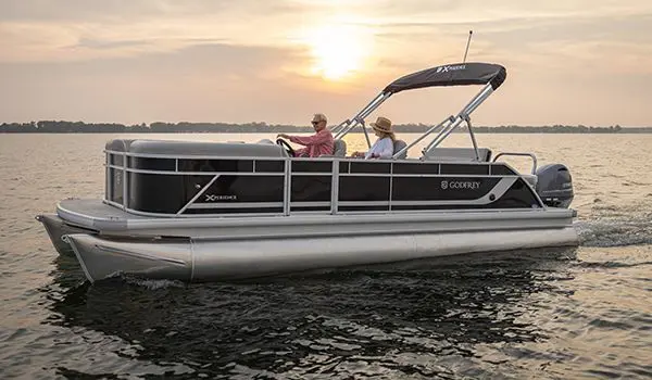 Side profile of a Godfrey Xperience Lounge pontoon boat on the lake at sunset.