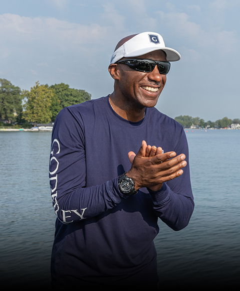 Man smiles, wearing a white Godfrey visor. 