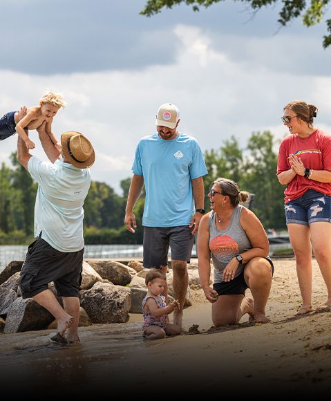 Family playing on beach wearing Godfrey t-shirts. 