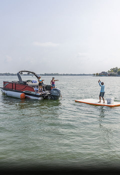 Man standing on a Godfrey inflatable mat with Godfrey branded cooler.
