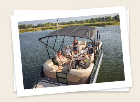 A family enjoying time together under the bimini on a Godfrey pontoon boat.