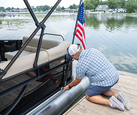 Man installing an American Flag to on the side of a Godfrey Pontoon Boat with a toolless attachment system.
