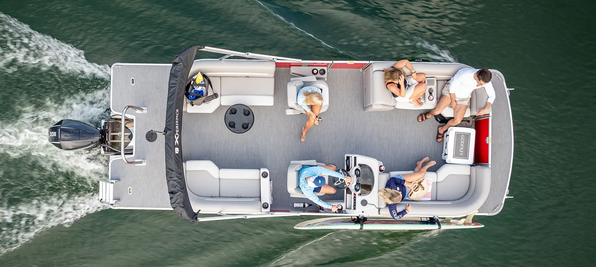 Overhead view of a Godfrey Pontoon Boat cruising on the water with a surf board attached to the side with a toolless accessory attachment system.