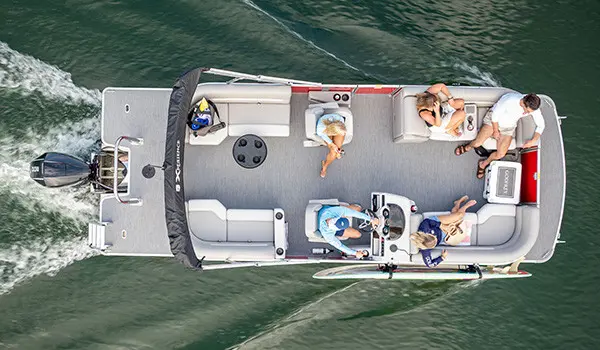 Overhead view of a Godfrey Pontoon Boat cruising on the water with a surf board attached to the side with a toolless accessory attachment system.