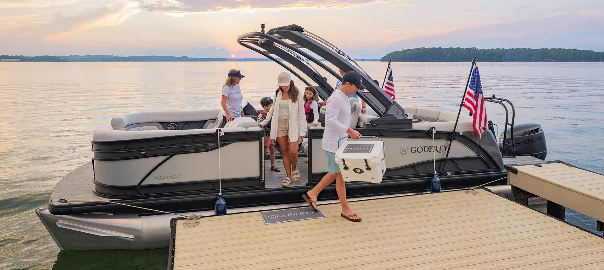 Family exits a parked ponton boat with American flags attached to its side using a toolless boat accessory attachment system.