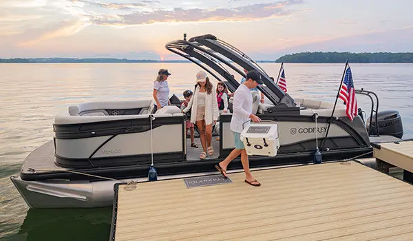 Family exits a parked ponton boat with American flags attached to its side using a toolless boat accessory attachment system.