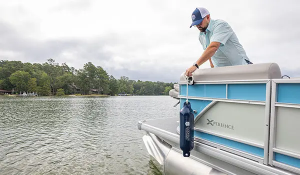 Man attaching boat bumpers to side of a Pontoon with a toolless boat accessory attachment system.