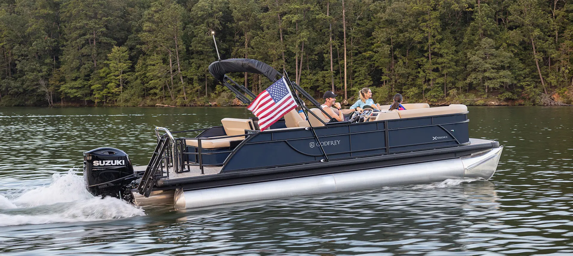 Pontoon boat cruising across the water with an American flag attached by a toolless boat accessory attachment system.