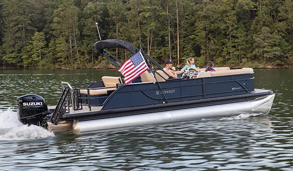 Pontoon boat cruising across the water with an American flag attached by a toolless boat accessory attachment system.