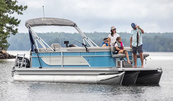 Man shows fish he caught to family on the front of a Godfrey Pontoon boat.