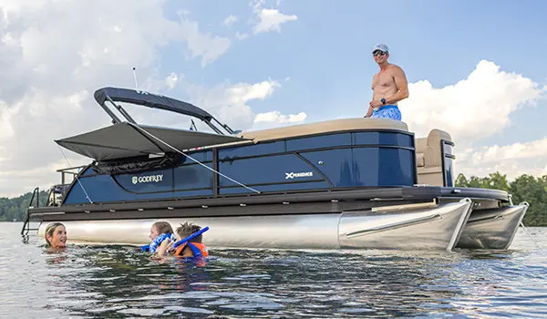 Family lounges on the front of a pontoon boat with American flags attached by a toolless boat accessory attachment system.