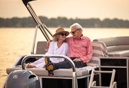A couple cuddling on the lounge seat on the stern of a Godfrey Xperience pontoon boat.