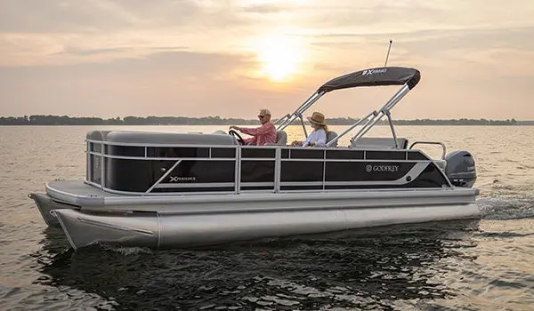 Side profile of a Godfrey Xperience pontoon boat cruising on a lake.