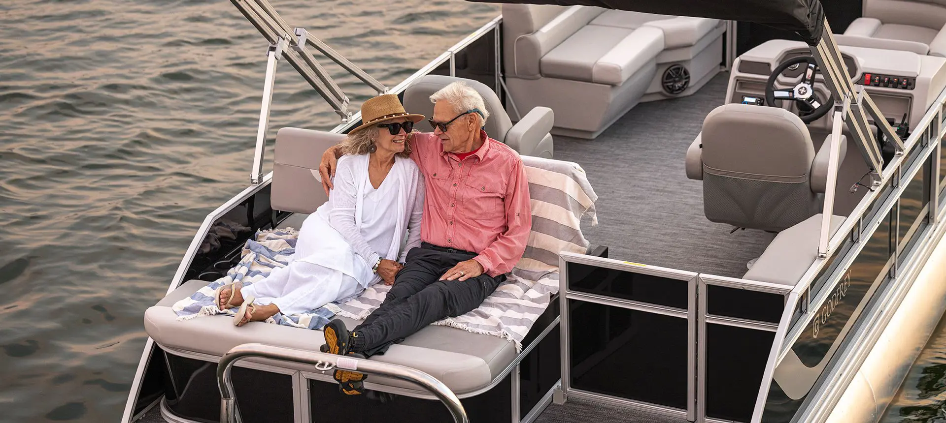 A couple relaxing closely on the stern of a Godfrey Xperience pontoon boat.
