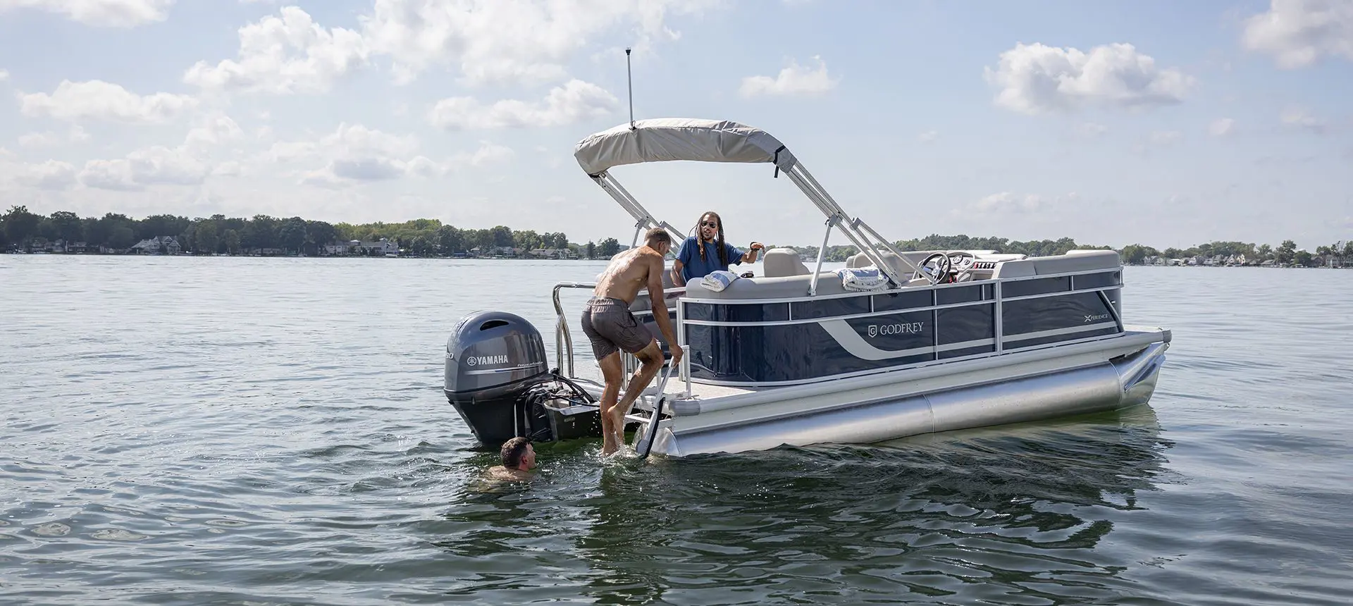 Man climbing up the stern ladder onto a Godfrey Xperience pontoon boat.