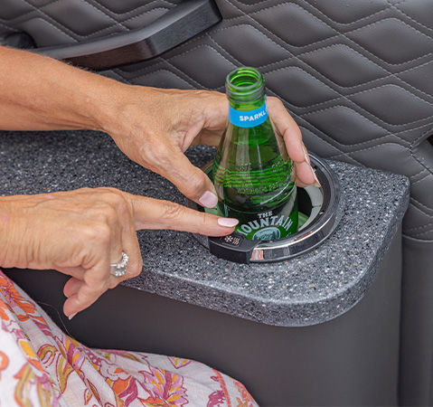 A person using the heated & cooled cupholder on a Godfrey pontoon boat with an entertainment layout.