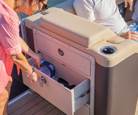 Woman removing hat from storage compartment on a Godfrey Entertainment Pontoon Boat.