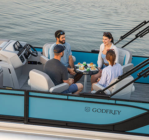 4 people sitting at the premium captain's chairs on a Godfrey pontoon boat with a Quad Social (QS) layout.
