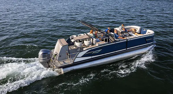 Side profile of a Godfrey AquaPatio pontoon boat cruising on a lake.