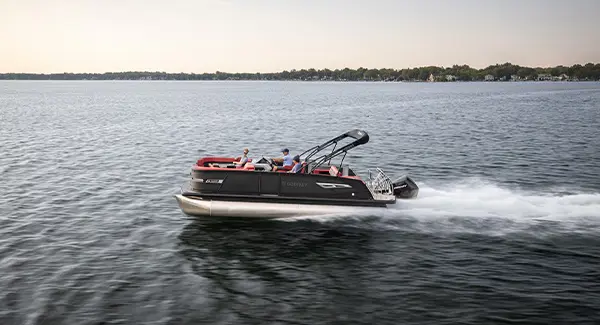 Side profile of a black Godfrey AquaPatio pontoon boat speeding across a lake.