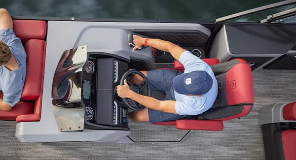 Overhead view of a man sitting at the helm of a Godfrey AquaPatio pontoon boat.