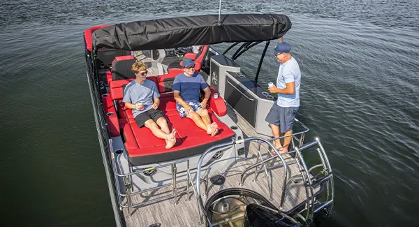2 people relaxing on the swingback seat on a Godfrey AquaPatio pontoon boat.