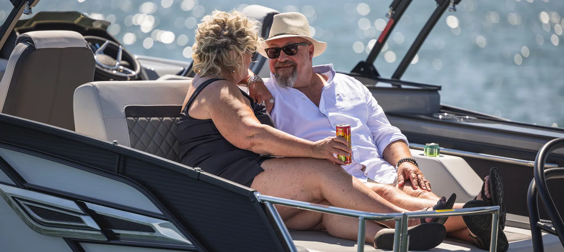 A couple enjoying each others presence on the swingback seat of a Godfrey AquaPatio pontoon boat.