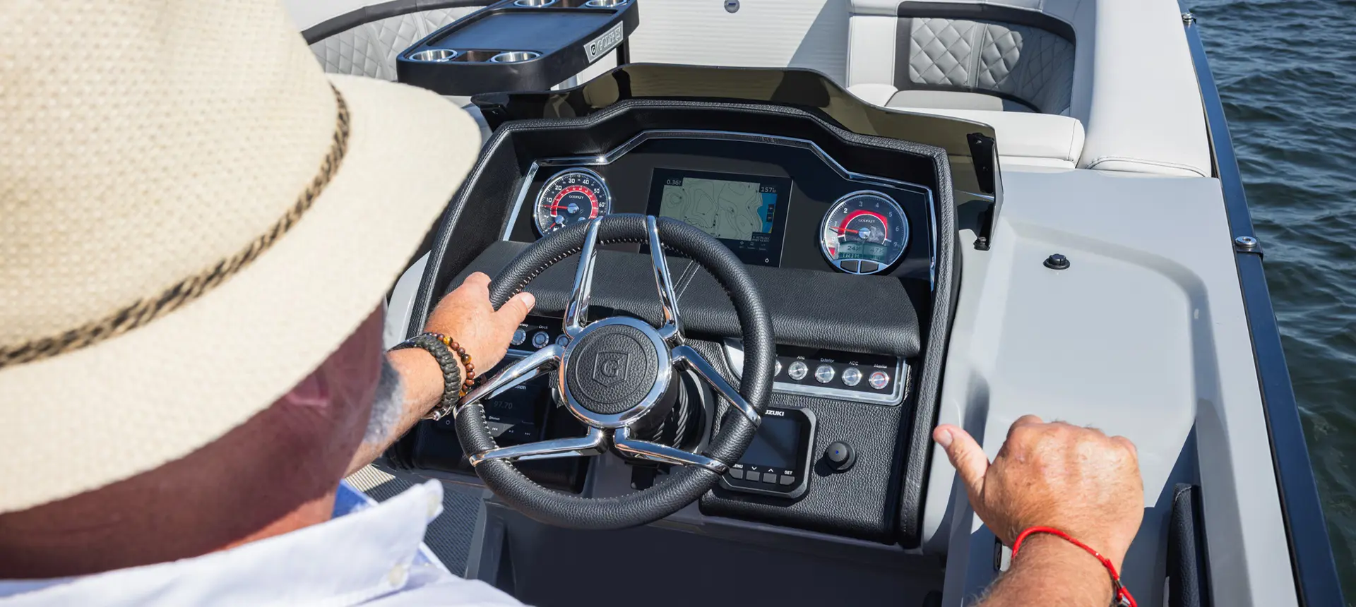 Over-the-shoulder view of a man at the helm and steering a Godfrey AquaPatio pontoon boat.
