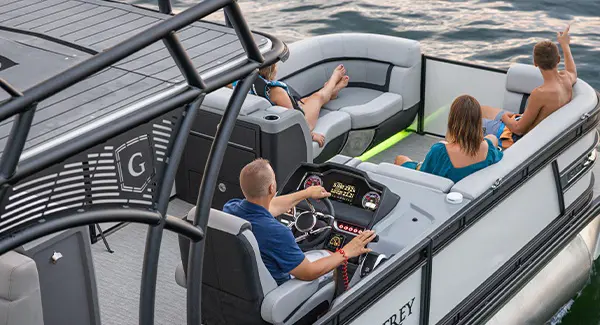 Aerial view of 4 people cruising the lake on a Godfrey AquaPatio pontoon boat.